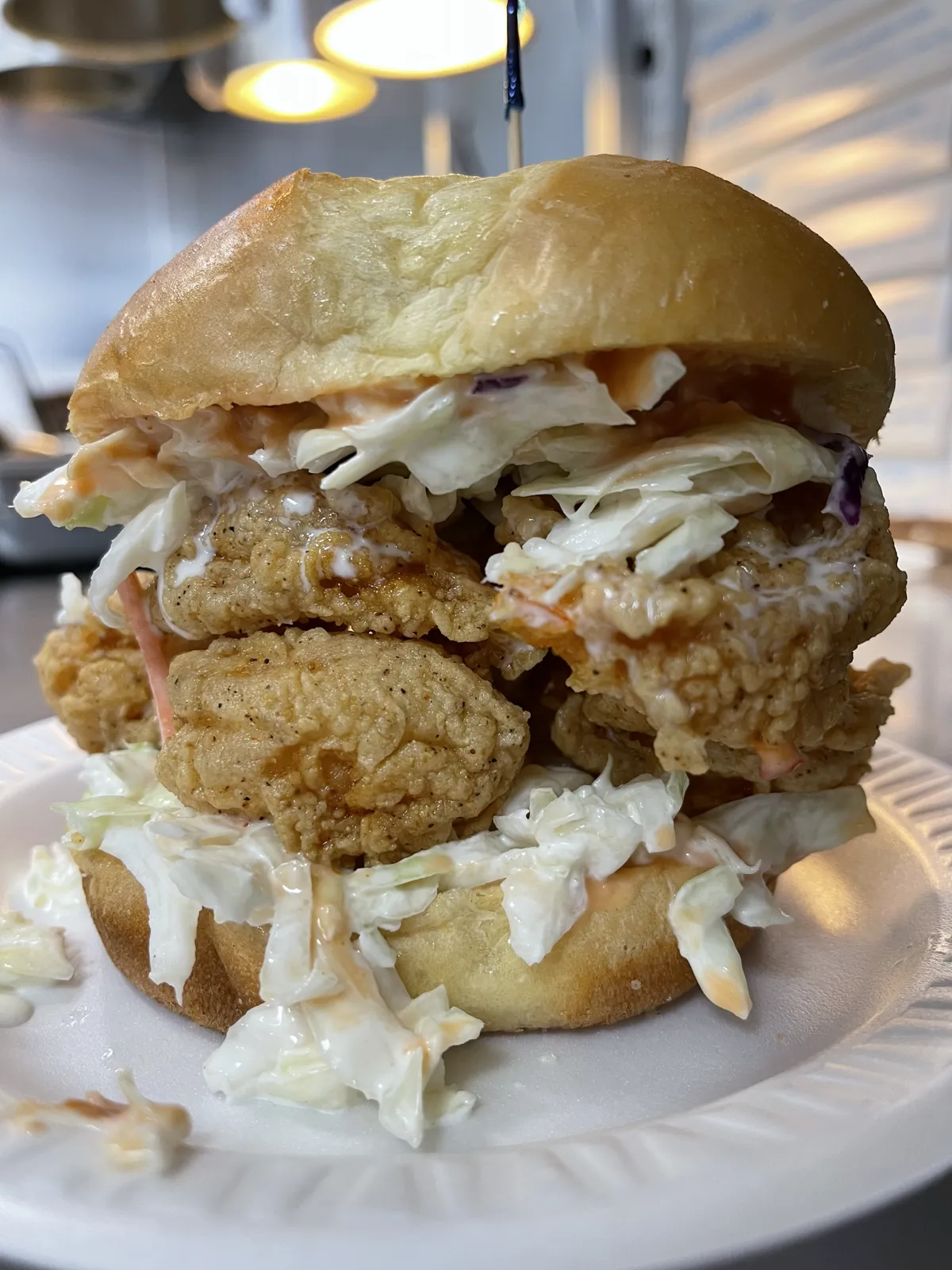 Fried fish sandwich piled with coleslaw at Fountain View Fish Market in Houston